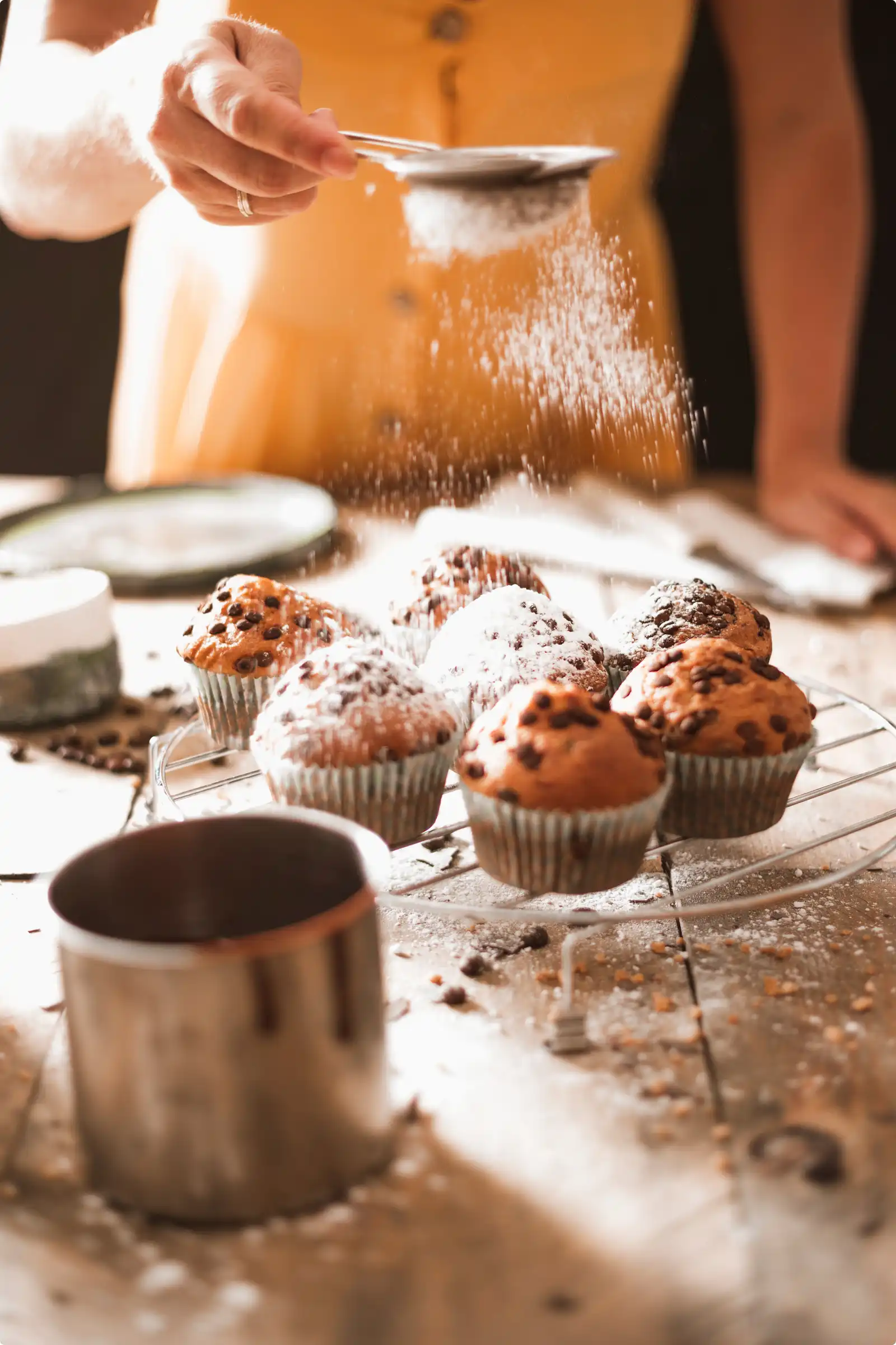 Roxane saupoudre du sucre glace sur des muffins tout juste sortis du four